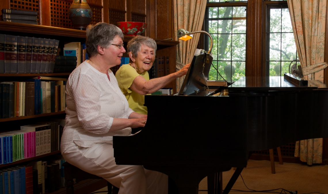Residents at the BA play piano together.